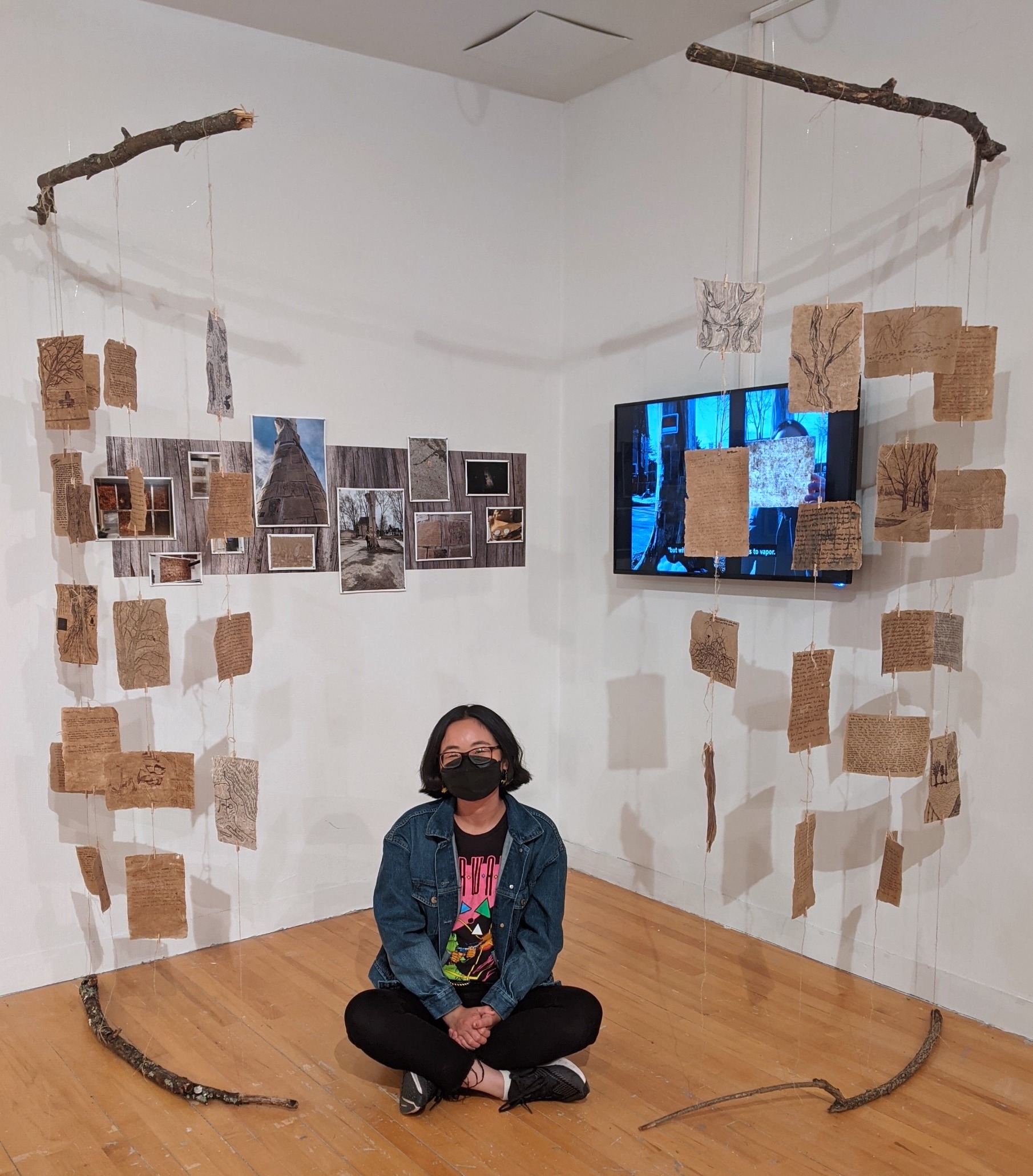 The artist sitting cross-legged in front of the multi-media gallery installation of Treehugger